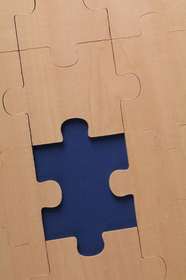 Wooden puzzle with a single missing piece on a dark background, perfect for themes of incompleteness.